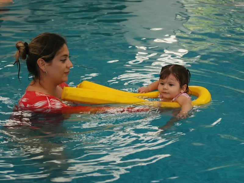 Instructor giving a one-on-one lesson to a toddler holding a float